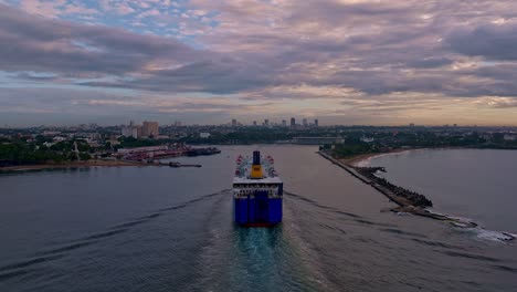 Back-view-of-ferry-boat-entering-in-port-with-Santo-Domingo-city-in-background-on-cloudy-day,-Dominican-Republic