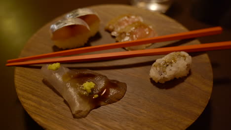 Minimalistische-Sushi-Küche-Präsentiert-Auf-Holzscheibe-Mit-Stäbchen-Im-Avantgarde-Restaurant