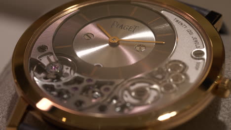 Luxurious-gold-Piaget-wristwatch-mechanical-clockwork-dial-detail-shining-under-display-light