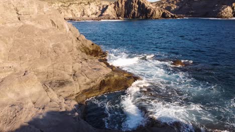 Aerial-of-cliff-waves-crashing-on-beautiful-rocks,-natural-pool,-forward,-day