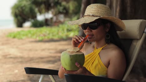 Bild-Einer-Frau,-Die-Sich-Am-Strand-Entspannt-Und-Dabei-Frischen-Kokosnusssaft-Trinkt