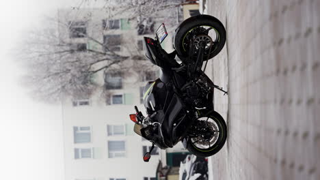 Moto-Kawasaki-Negra-En-La-Nieve,-Toma-Vertical-En-Cámara-Lenta