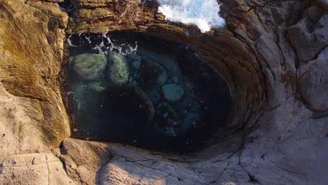 Amazing-top-down-aerial-shot-of-natural-circular-pool,-waves-crashing-inside