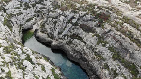Malta,-Gozo-island-Ghasri-Valley-mediterranean-sea-canyon,-aerial-view-of-rocky-cliff-and-hidden-beach