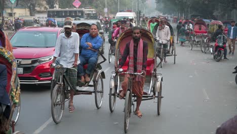 Cinematic-shot-of-Bangladeshi-commuters-riding-on-rickshaws-on-a-busy-road-in-Dhaka