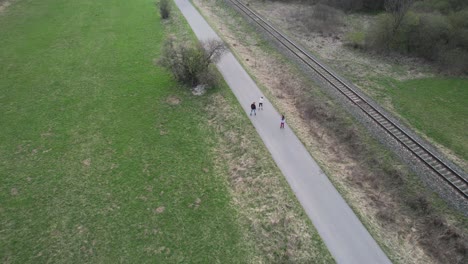 Aerial-tracking-shot-of-a-family-rollerskating-at-the-side-of-a-railway-track