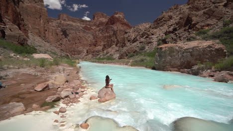Junge-Frau-Im-Bikini-Sitzt-Auf-Einem-Felsen-Am-Türkisfarbenen-Flusswasser,-Grand-Canyon-Nationalpark,-Arizona,-USA