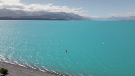 Wing-foil-surfing-on-striking-blue-Lake-Pukaki-in-strong-wind,-Southland