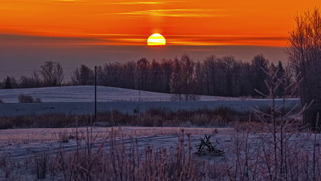 Time-lapse-of-yellow-sun-rising-in-golden-sky-over-snowy-landscape-at-sunrise