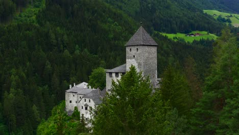 Ascending-aerial-shot-over-an-ancient-stone-castle-surrounded-by-green-trees