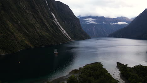 Single-yacht-anchored-in-scenic-Harrison-Cove,-Milford-Sound,-New-Zealand-aerial