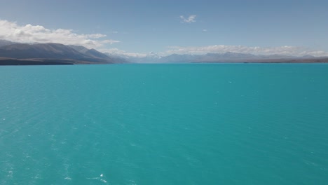 Drone-flight-over-stunning-blue-glacial-Lake-Pukaki,-New-Zealand