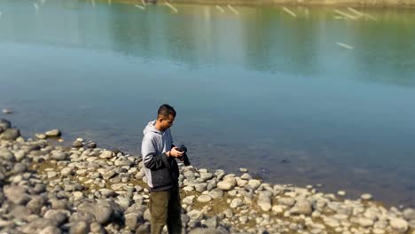 Male-Photographer-Taking-Photos-On-Rocky-Riverbank-In-Bangladesh