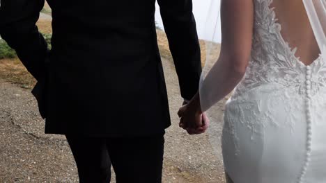 Groom-and-bride-walk-hand-in-hand-at-their-wedding