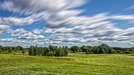 White-fluffy-clouds-flow-above-green-rural-landscape-on-sunny-day,-fusion-time-lapse