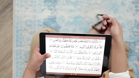 reading-Quran-scripture-from-iPad-holding-prayer-beads,-Islamic-Dhikr