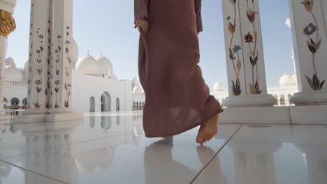Muslim-in-abaya-enter-mosque-hall-with-white-marble-floor,-UAE
