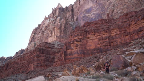 Female-Hiker-Walking-Under-Redstone-Cliffs-in-Grand-Canyon-National-Park,-Arizona-USA,-Slow-Motion
