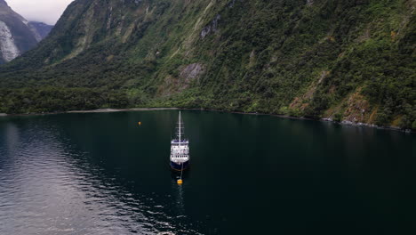 Aerial-arc-of-the-Milford-Mariner-in-Harrison-Cove,-Milford-Sound,-New-Zealand