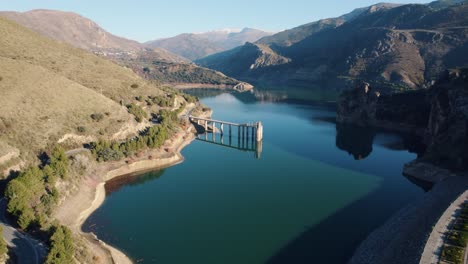 Drohnenflug-über-Den-Canales-Stausee-In-Güéjar,-Sierra-Nevada-In-Spanien,-Zeigt-Die-Hohen-Berge-Und-Das-Wunderschöne-Blaue-Wasser