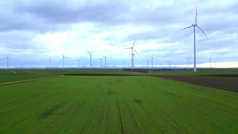Wind-Turbines-Generating-Electricity-In-Agricultural-Field---aerial-drone-shot