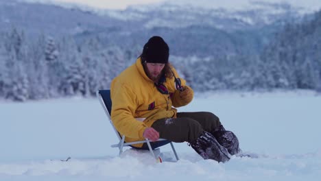 Hombre-Pescando-En-El-Hielo-En-Un-Lago-Congelado-En-Indre-Fosen,-Noruega---Ancho