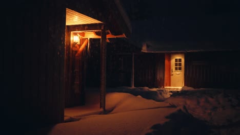 Beleuchtete-Hütten-In-Der-Winternacht-Mit-Fallendem-Schnee