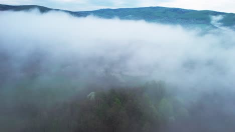 Cinematic-aerial-shot-overhead-dense-fog-lying-in-the-countryside-valley