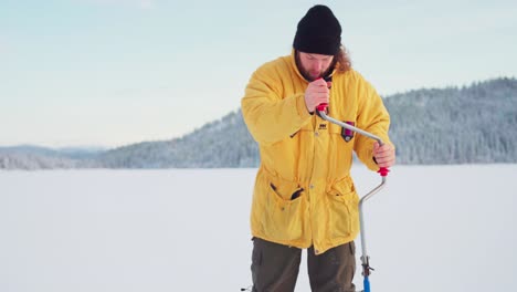 A-Guy-With-Ice-Fishing-Drill-Digging-A-Hole-In-Frozen-Lake