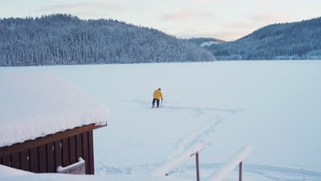 Panoramic-View-Of-Winter-Landscape-With-Man-Seated-On-A-Chair-Fishing-In-Frozen-Lake