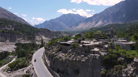Luftaufnahme-Eines-Rikscha-Fahrzeugs-Auf-Der-Karakoram-Autobahn-In-Nordpakistan,-Dorf-Und-Landschaft-Im-Hunza-Tal,-Drohnenaufnahme