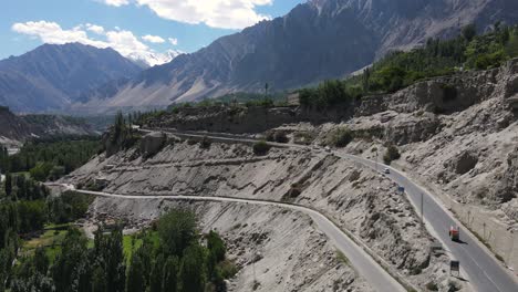 Aerial-View-of-Hunza-Valley,-Pakistan,-Road-Under-Mountains-on-Sunny-Summer-Day,-Drone-Shot