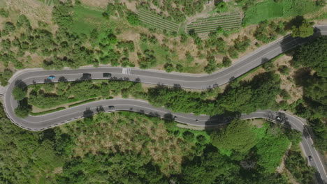 Top-down-aerial-footage-of-cars-driving-up-and-down-a-switch-back-windy-road-on-the-Amalfi-Coast