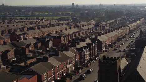 Aerial-view-reveals-rows-of-historic-terraced-houses-in-Dentons-Green,-St-Helens-with-a-long-road-at-sunrise