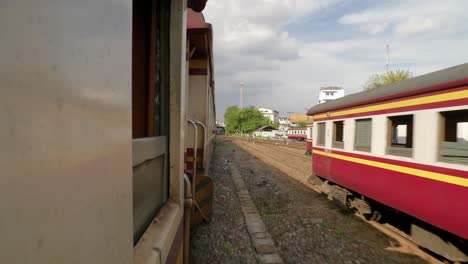 Blick-Auf-Fahrende-Züge,-Die-An-Anderen-Zügen-Auf-Gleisen-Am-Bahnhofsknotenpunkt-In-Thailand-Vorbeifahren