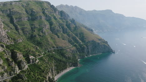 Wide-aerial-footage-on-the-Amalfi-coast-showing-cars-on-a-windy-road-and-the-mountains-meeting-the-coast-of-the-Mediterranean-Sea