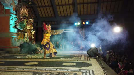 Balinese-Dancer-Performs-at-Stage-with-Gamelan-Players-Bali-Indonesia-Truna-Jaya-Choreography,-Art-at-Karangasem-Village-Wearing-Traditional-Unique-Fabrics-and-Hand-Fan