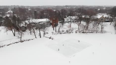 Aerial-of-a-family-playing-ice-hockey-in-their-backyard-homemade-rink-while-snowing