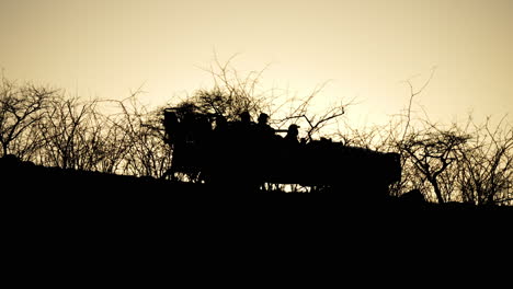 Eine-Silhouette-Eines-Safarifahrzeugs,-Die-Im-Goldenen-Licht-Des-Sonnenaufgangs-Oder-Sonnenuntergangs-Als-Statische-Aufnahme-Durch-Den-Afrikanischen-Busch-Fährt