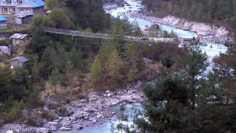 Einige-Yaks-überqueren-Eine-Schwingende-Brücke-über-Einen-Gletscherfluss,-Der-Von-Den-Schroffen-Bergen-Des-Himalaya-In-Nepal-Begrenzt-Wird