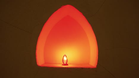 Alcove-illuminated-with-orange-lightbulb-at-Buddhist-temple,-Wat-Phra-Sri-Rattana-Mahathat,-Thailand