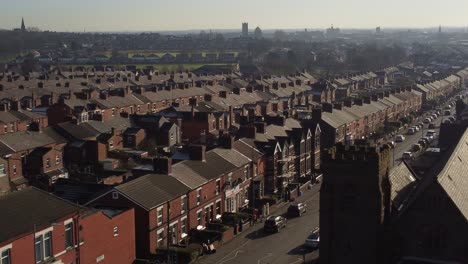 Aerial-view-across-terraced-houses-and-church-community-with-a-long-road-leading-towards-the-bustling-town-centre