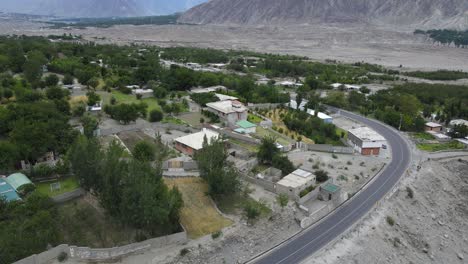 Aerial-View-of-Village-in-Hunza-Valley,-Pakistan,-Road-Traffic-and-Homes-in-Highlands