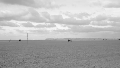 Menschen,-Die-Am-Sandstrand-An-Der-Küste-Von-Deauville-In-Der-Normandie,-Frankreich,-Spazieren-Gehen