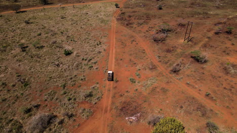 Ariel-drone-shot-following-a-safari-vehicle-through-a-dry-arid-African-dirt-road-while-taking-travellers-out-to-search-for-wild-animals