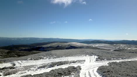 Ascending-aerial-shot-flying-over-a-snowy-path-in-a-mountainous-landscape-in-Manzaneda,-Galicia