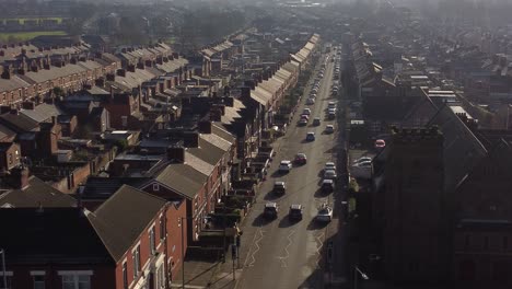 Aerial-rising-view-establishing-rows-of-Victorian-terraced-houses-with-a-long-road-leading-towards-the-bustling-town-centre-at-sunrise