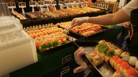 Fresh-sushi-rolls-being-put-on-trays-with-price-tags-for-purchase,-Phitsanulok,-Thailand
