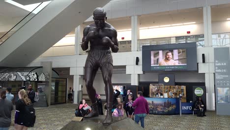 Joe-Lewis-Statue-in-Huntington-Center-with-people-walk-around,-pan-right-view