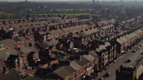 Aerial-descending-view-reveals-rows-of-historic-terraced-houses-in-Dentons-Green,-St-Helens-with-a-long-road-leading-towards-the-bustling-town-centre